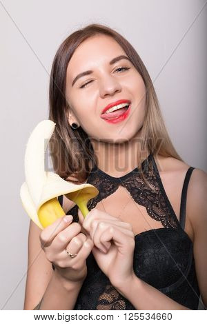 Young amazed woman in lacy lingerie holding a banana, she is going to eat a banana.