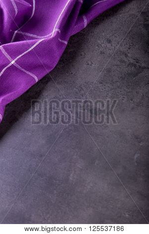 Top view of checkered kitchen purple tablecloth on concrete - stone - marble - wooden background. Free space for your text or products.