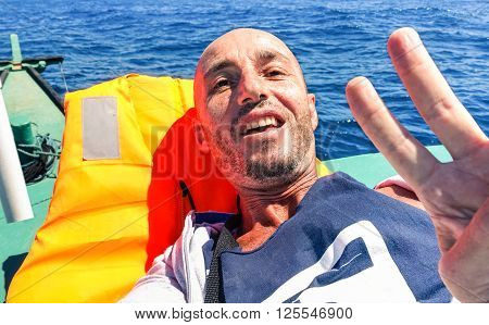 Man taking selfie on solo ocean crossing with tropical islands background - Tired male survivor to extreme travel experience - Concept of hard sea travel or clandestine migrant Mediterranean sea trip