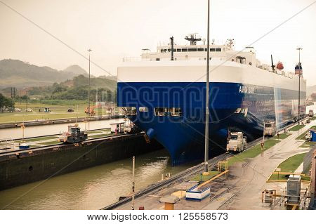 Panama City Panama - August 31 2015: Huge cargo ship enters the transit point of Miraflores Locks in Panama Canal on a rainy day. Central America