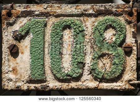 Old retro weathered cast iron plate with number 108