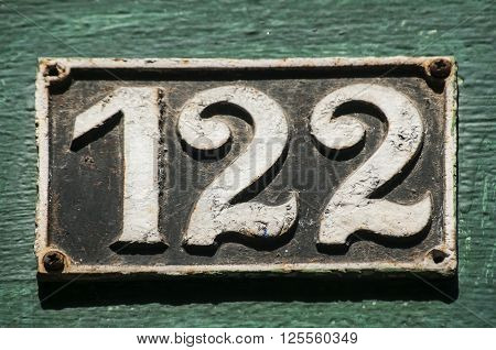 Old retro weathered cast iron plate with number 122