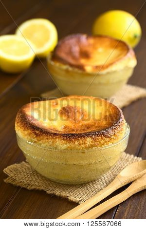 Homemade lemon souffle in glass bowls photographed on dark wood with natural light (Selective Focus Focus on the front of the first souffle)