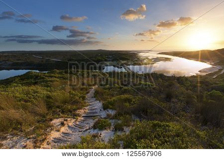 Cloudy sunrise over a quiet lagoon with cloud patterns reflected in the water
