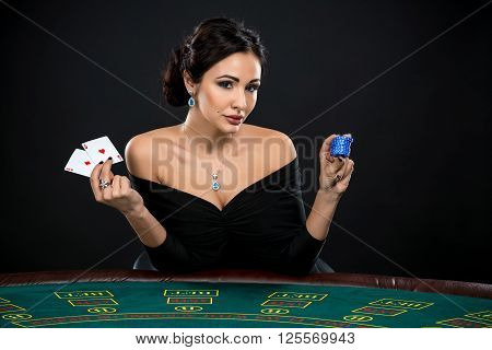 sexy woman with poker cards and chips. Female player in a beautiful black dress. girl sitting at the poker table
