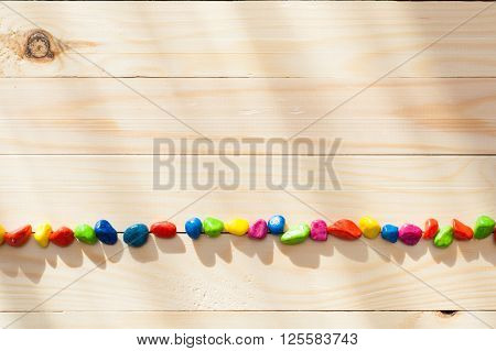 Colored stones on textured board in sunny weather with light from the window.