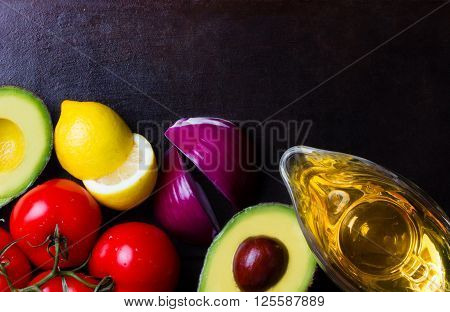 Ingredients for latin american sauce guacamole on black stone background