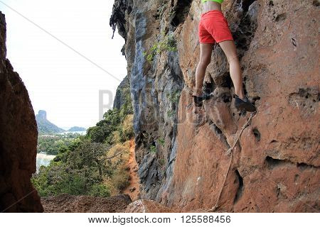 young woman rock climber climbing at seaside mountain rock