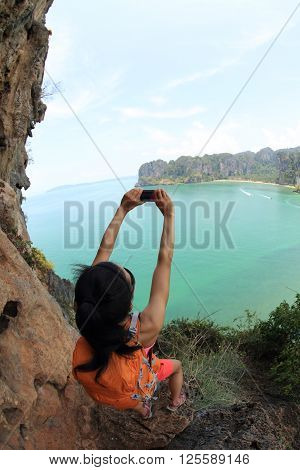 young woman hiker use smartphone taking photo on seaside