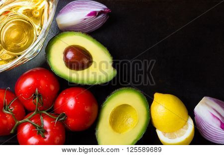 Ingredients for latin american sauce guacamole on black stone background