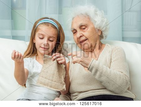ganddaughter learning to embroider with granny on sofa