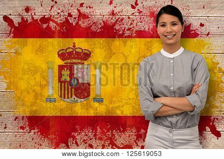Selfassured businesswoman with folded arms against spain flag in grunge effect