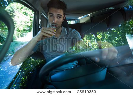Portrait of slumped man drinking alcohol while driving car