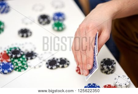 leisure, games, friendship, gambling and entertainment - close up of male hand with playing cards and chips at home