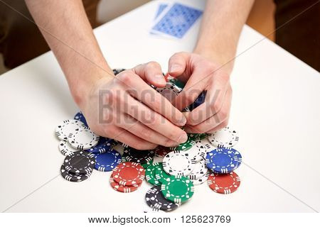 leisure, games, gambling and entertainment - close up of male hands with casino chips and playing cards making bet or taking win at home
