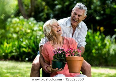 Senior couple with flower pots enjoying in yard