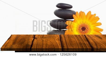 Wooden floor against unlighted candles pebble stack an orange gerbera