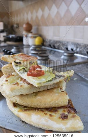 pieces of assorted homemade pizza on a hob in a domestic kitchen