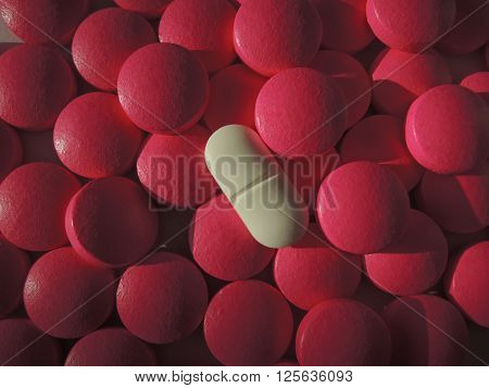 Heap of drugs with a pink pill among white pills