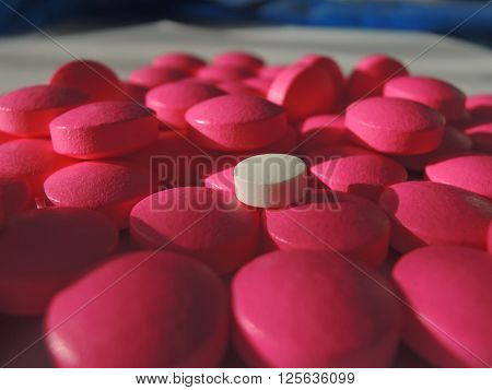 Heap of drugs with a pink pill among white pills