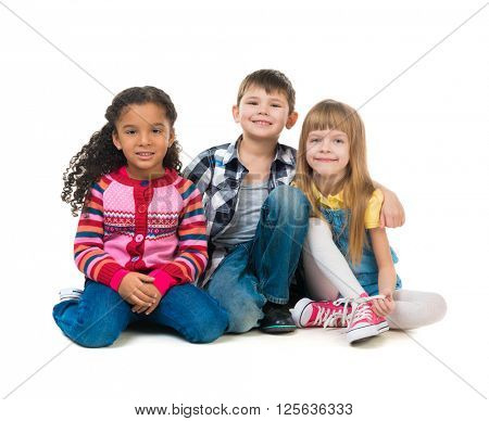 thre cheerful kids sitting on the floor in a studio isolated on white background