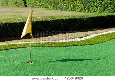 Mini golf with hole on green and flag in the evening