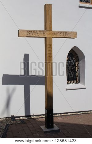 Wooden cross with a years of Saint Missions and its shadow on the wall of the gothic church in Svaty Jur Slovakia. Traditional gothic window beside.