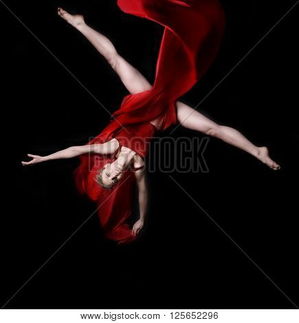 Young woman gymnast wearing red dress on rope on black background