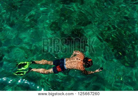 Man snorkeling with fins and filming with action camera