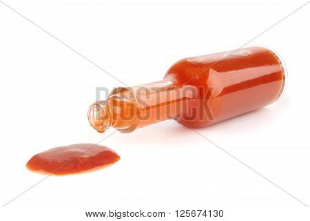 bottle of hot sauce is spilling liquid on white background