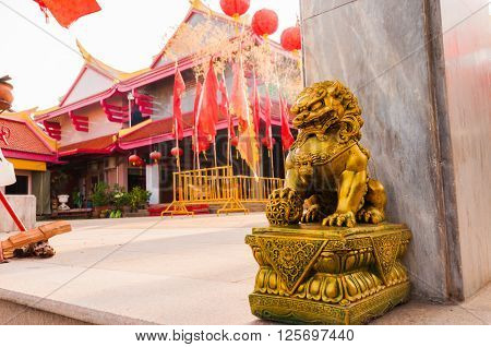 Golden chinese lion guardian sculture in front of the gate to the temple