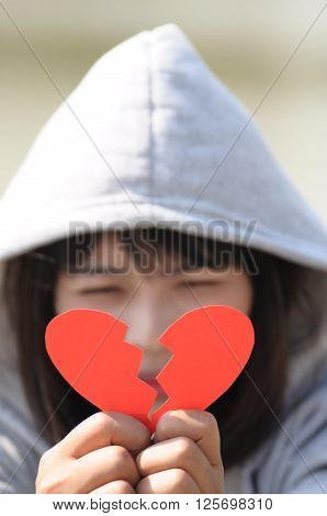Sad Woman Looking to Red Broken Heart on Hands