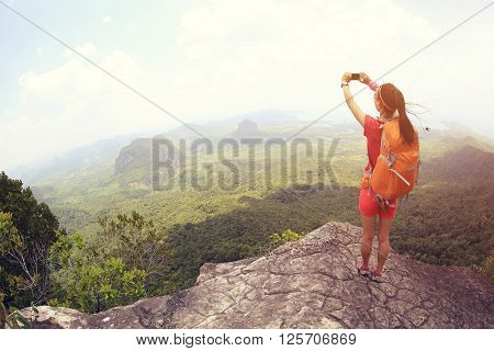 young woman hiker use smartphone taking photo on seaside mountain top