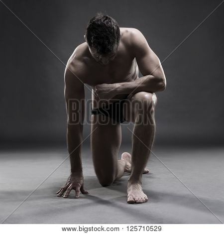 Handsome muscular bodybuilder posing on gray background. Low key studio shot. Sexy male body