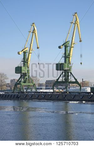 ST. PETERSBURG, RUSSIA - FEBRUARY 17, 2016: Two cranes working at the pier of the Kanonersky channel. The St. Petersburg cargo port