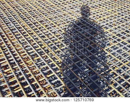 The shadow of a construction worker on the rebar grids. Location shadows of the frame diagonally