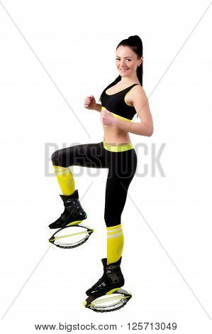 slender smiling brunette girl in kangoo jamps shoes doing exercises looks at the camera. Isolated on white background in studio