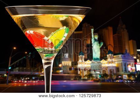 Close-up picture of evening city background with full martini glass with two dibs inside