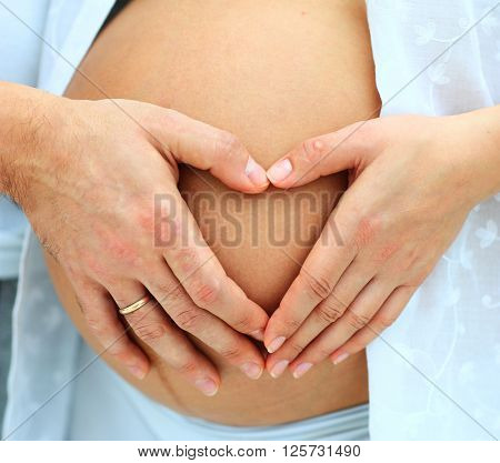 close-up image of the heart by mom's and dad's handson her babu bump