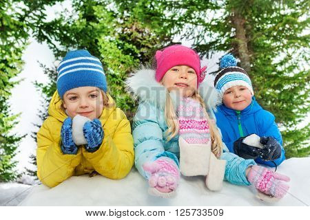 Group of kids boys and girls play with snow outside on cold winter day