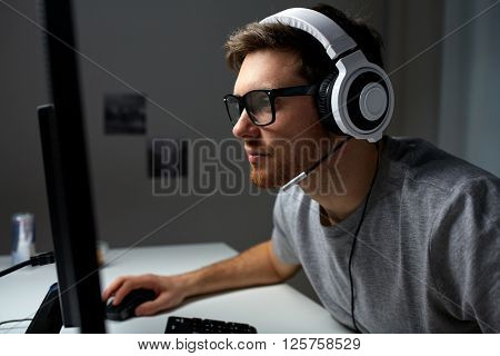 technology, gaming, entertainment, let's play and people concept - young man in headset and glasses with pc computer playing game at home and streaming playthrough or walkthrough video