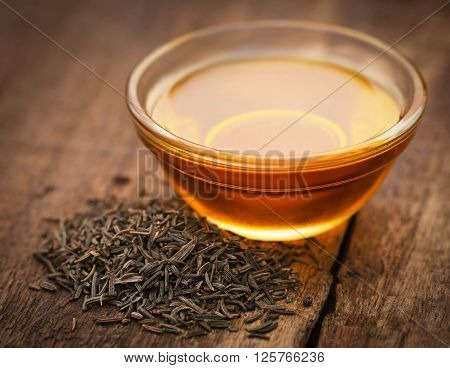 Caraway seeds with essential oil on wooden surface