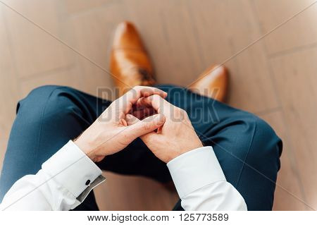 Man Sits With Hands Clasped