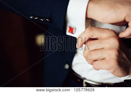 groom in the morning on the wedding day buttoning cuffs his hands on his suit. Close up