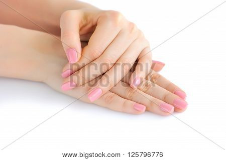Closeup of hands of a young woman with pink manicure on nails against white background