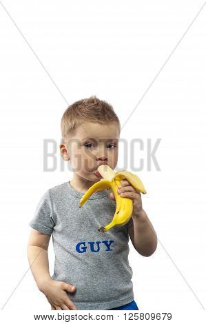 Charming three years old boy eating banana.