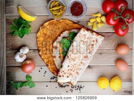 Lahmacun on a wooden table with ingredients. Turkish pizza
