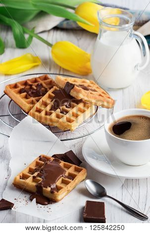 Fresh coffee for breakfast with waffles on a wooden background