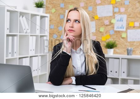 Thoughtful businesswoman at desk in office, close up