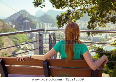 girl tourist sitting and resting on the bench on the background Rio de Janeiro. view from Pao de Acucar